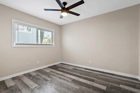 an empty bedroom with a ceiling fan and a window