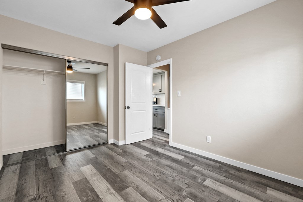an empty living room with a ceiling fan and a door to a bathroom