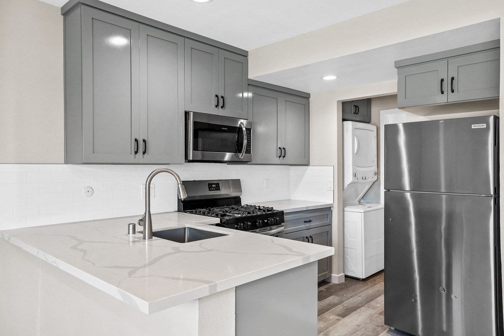a kitchen with stainless steel appliances and white quartz counter tops