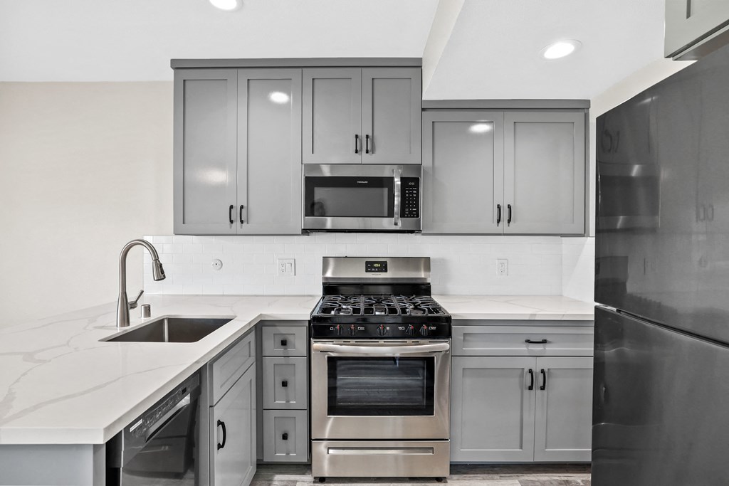 an all white kitchen with stainless steel appliances and gray cabinets