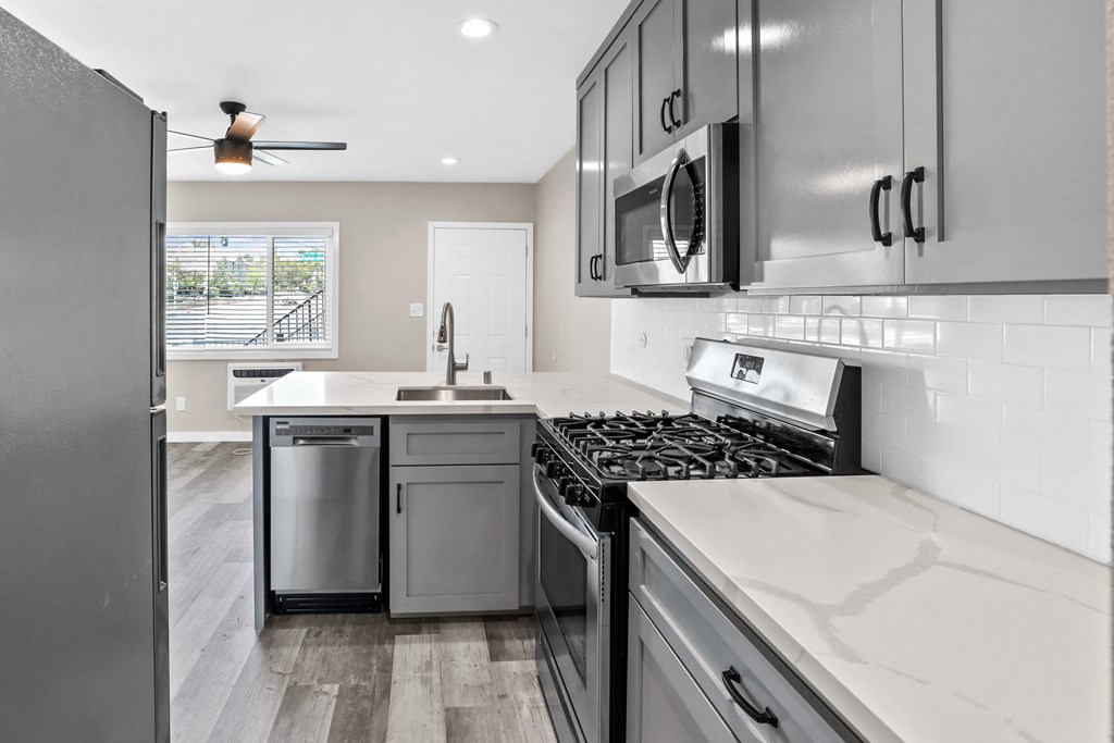 an updated kitchen with stainless steel appliances and white counter tops