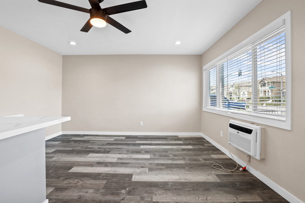 an empty living room with a ceiling fan and a window