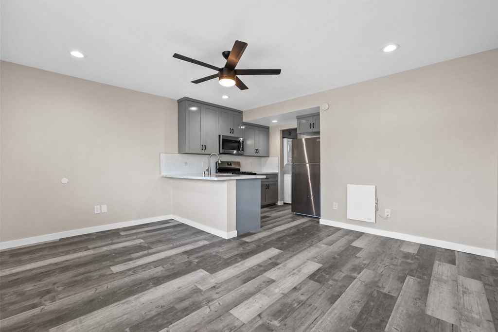 an empty living room and kitchen with a ceiling fan