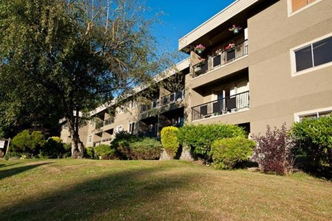 A building with a balcony and a tree in front of it.