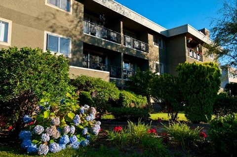 A building with a balcony and a garden in front.