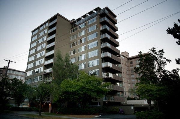A tall residential building with balconies on the upper floors.
