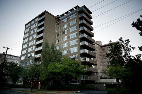 A tall residential building with balconies on the upper floors.