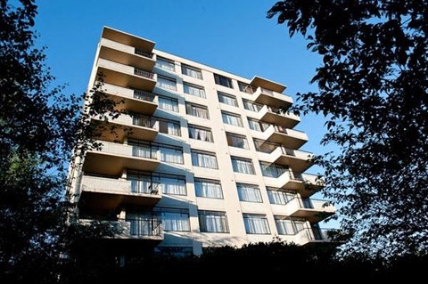 A tall residential building with balconies on the upper floors.