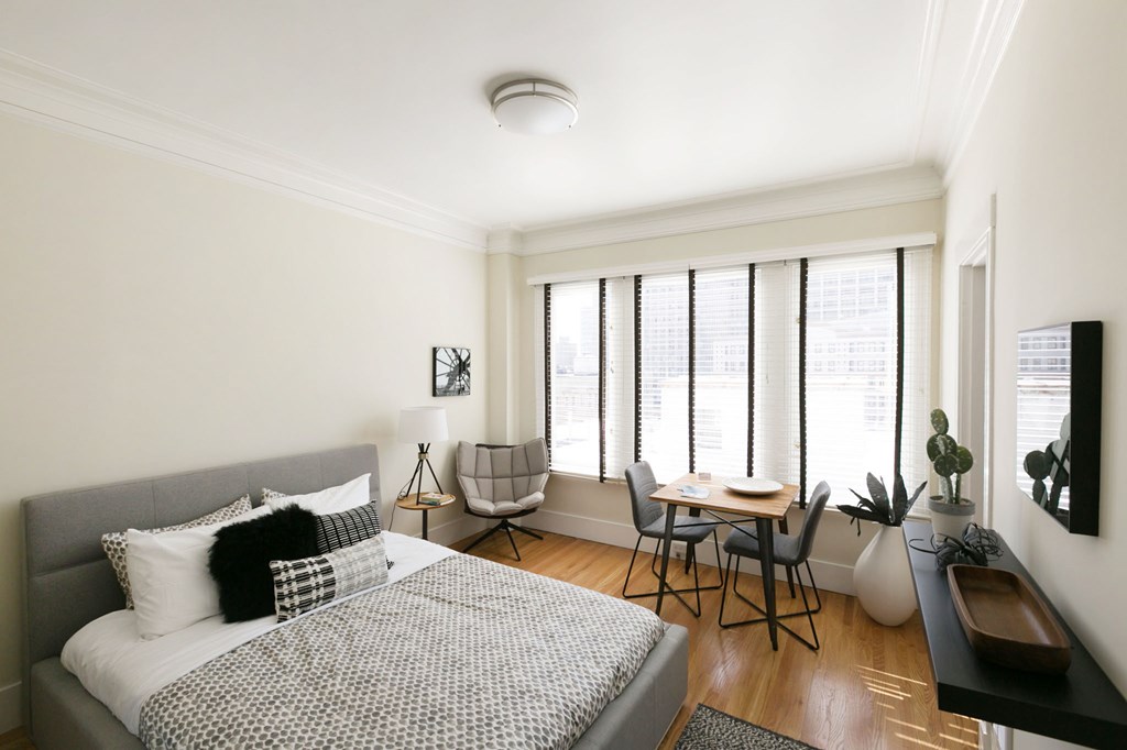 a bedroom with a bed and a desk and windows