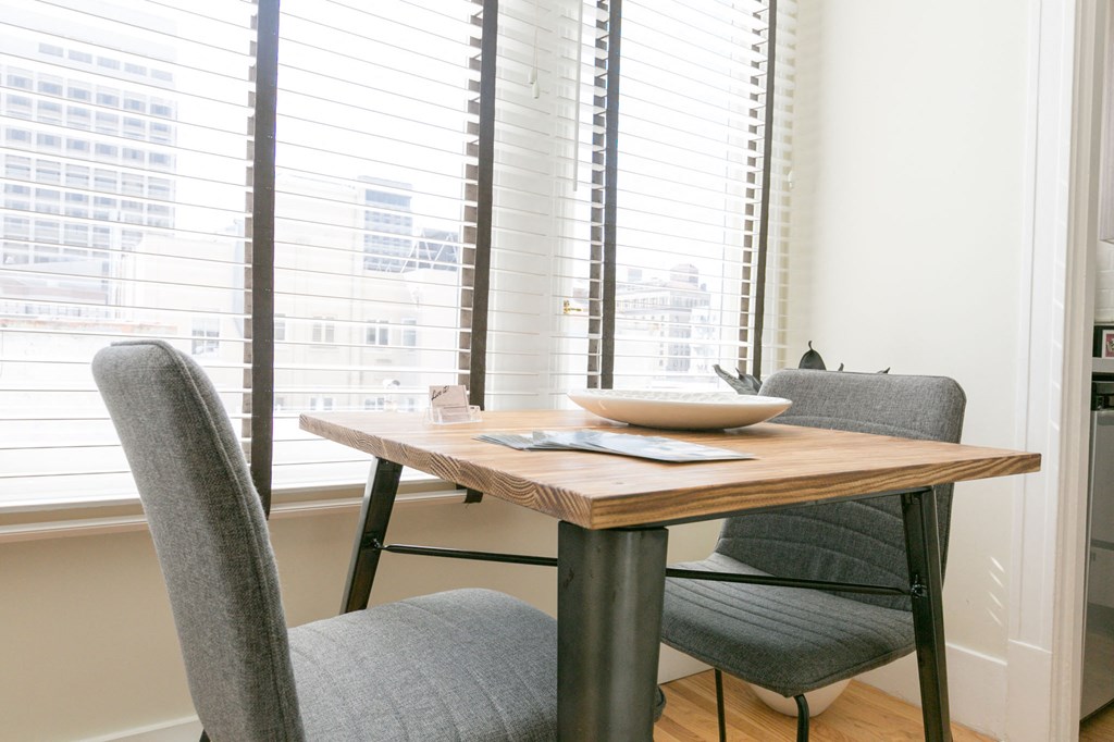 a dining room table with two chairs and a window with blinds