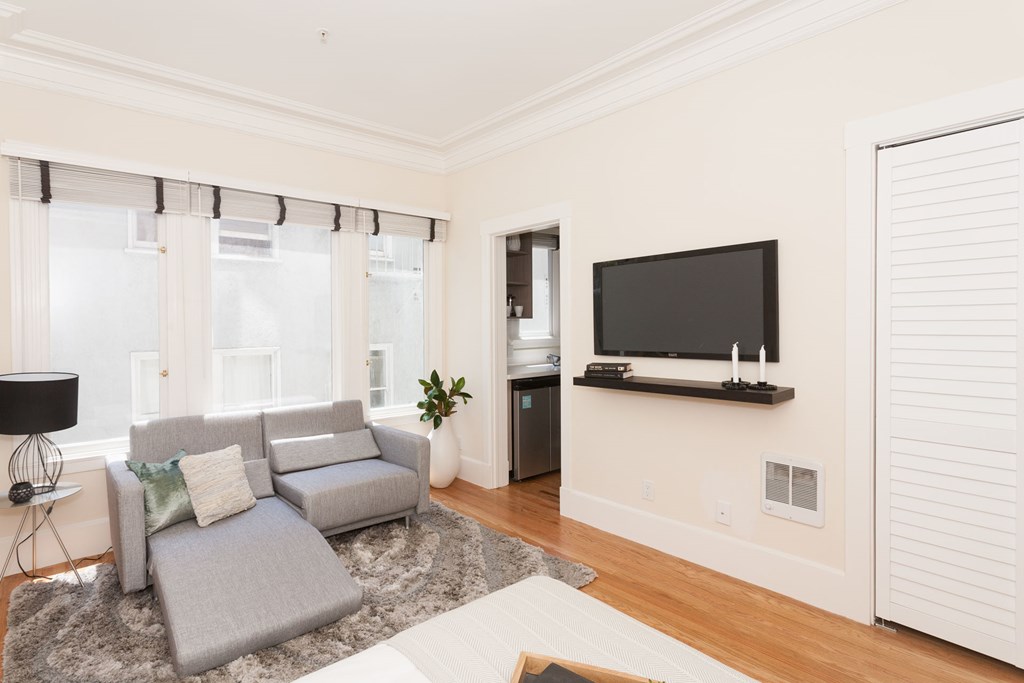 A living room with a grey sofa and a black television.