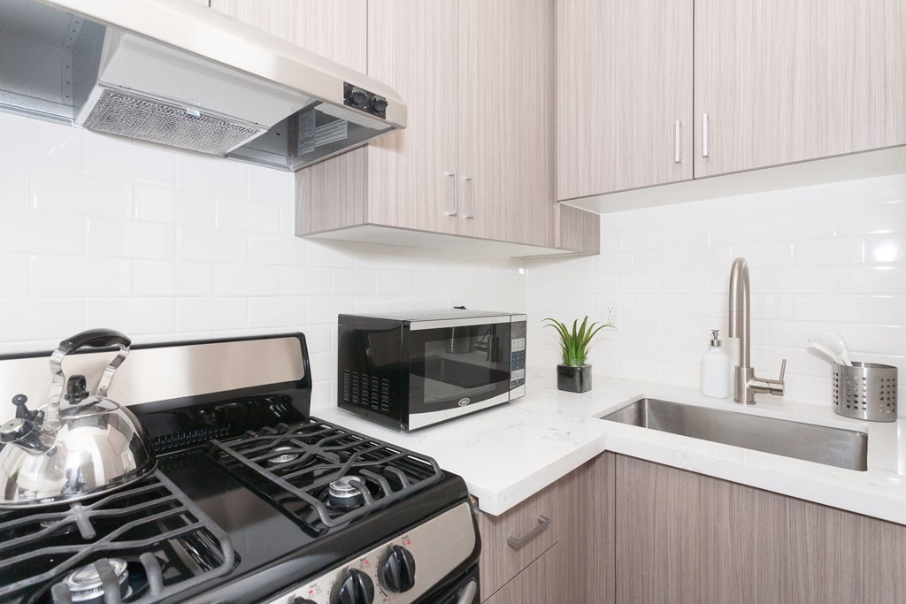 A modern kitchen with a black stove and white countertops.