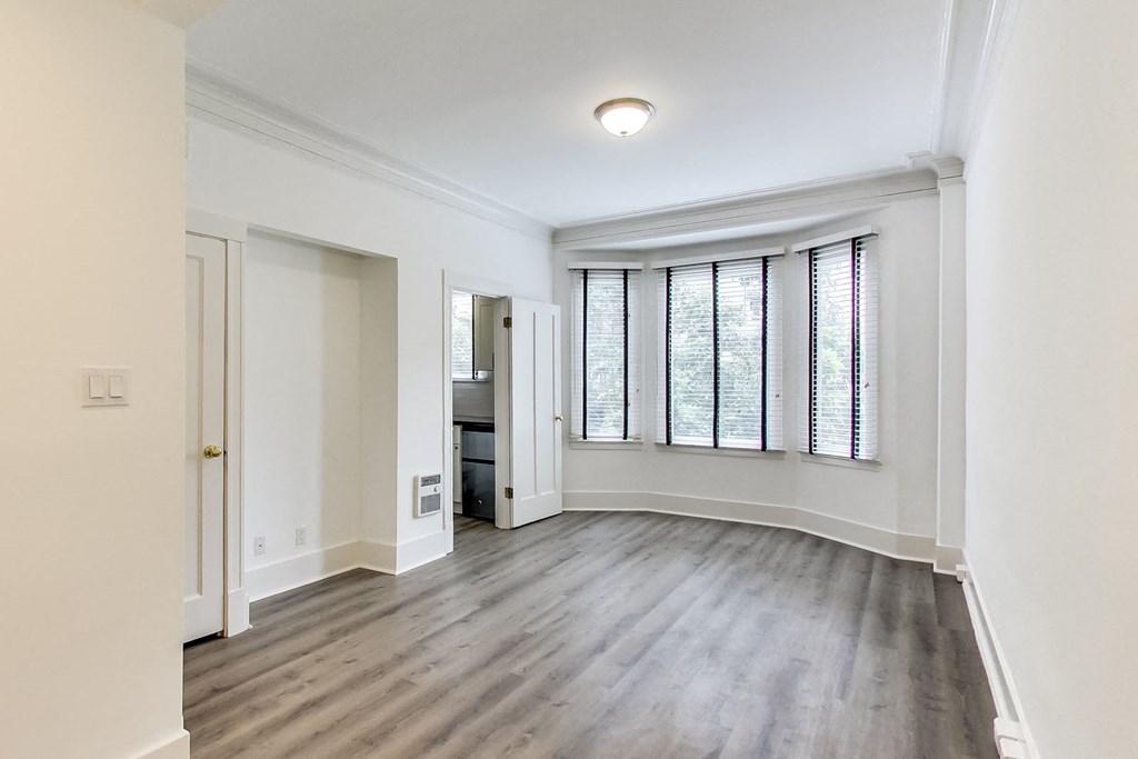 an empty living room with white walls and a large window