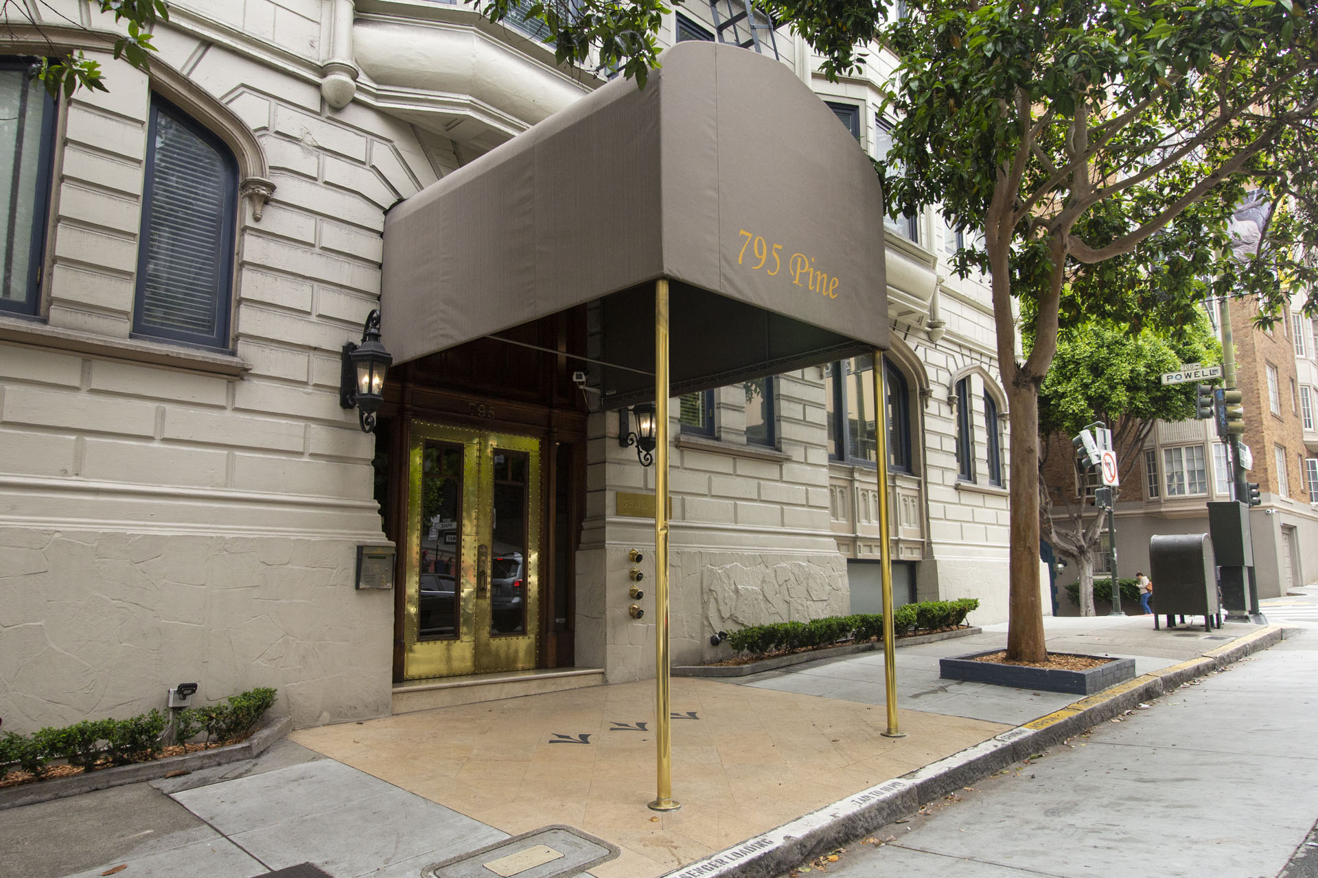 The entrance to a building with a brown awning and gold door.