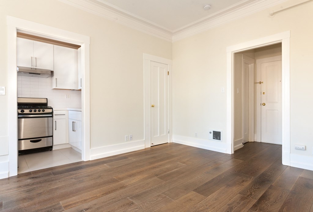 a living room with a hard wood floor and a doorway into a kitchen