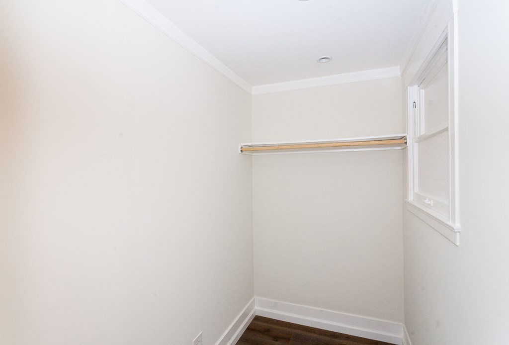 a small closet with a white wall and a window
