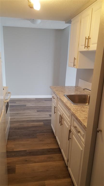 A kitchen with wooden floors and white cabinets.