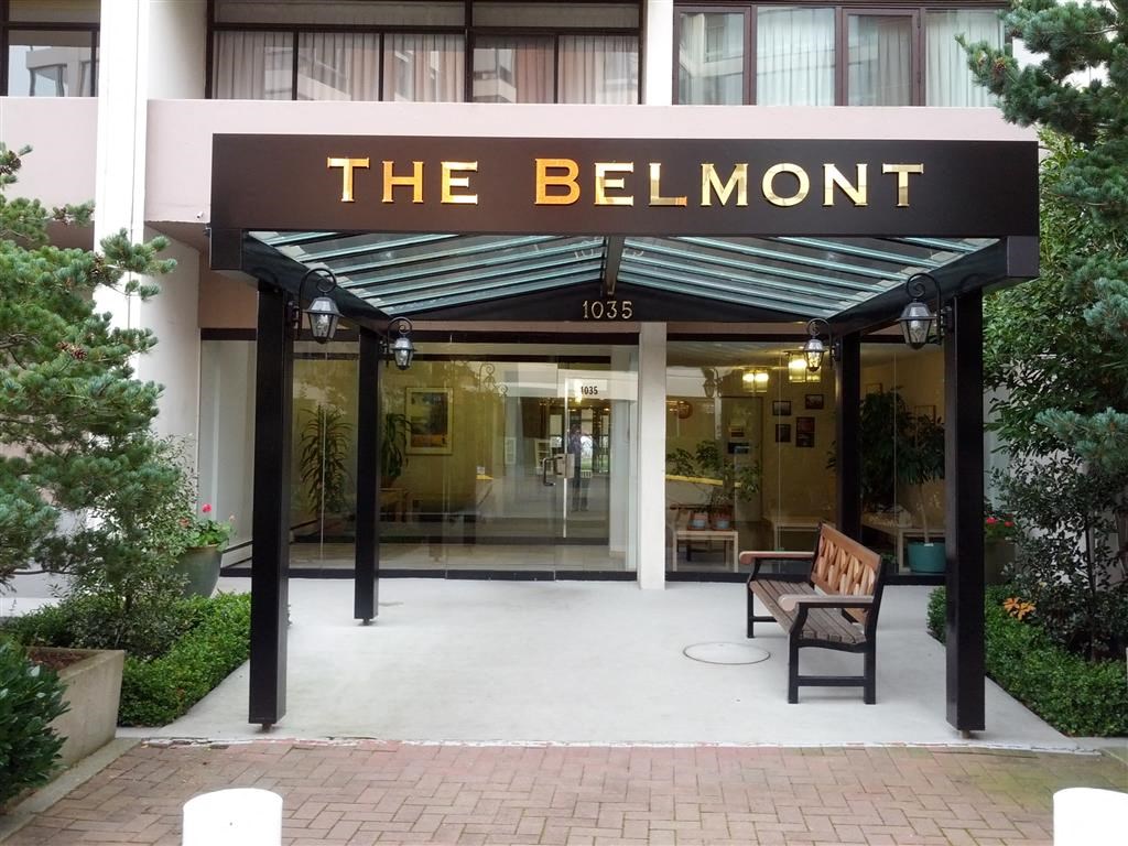The Belmont building has a black awning and a bench outside.