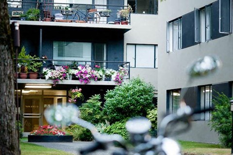 A motorcycle is parked in front of a building with a balcony.