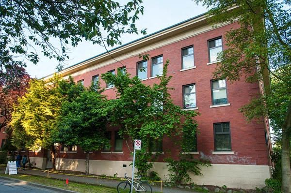 A red brick building with a no parking sign in front.
