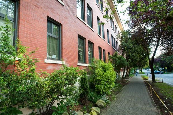 A red brick building with green bushes in front.