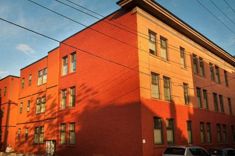 A red brick building with a parking lot in front.