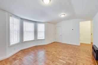 an empty living room with wood flooring and windows