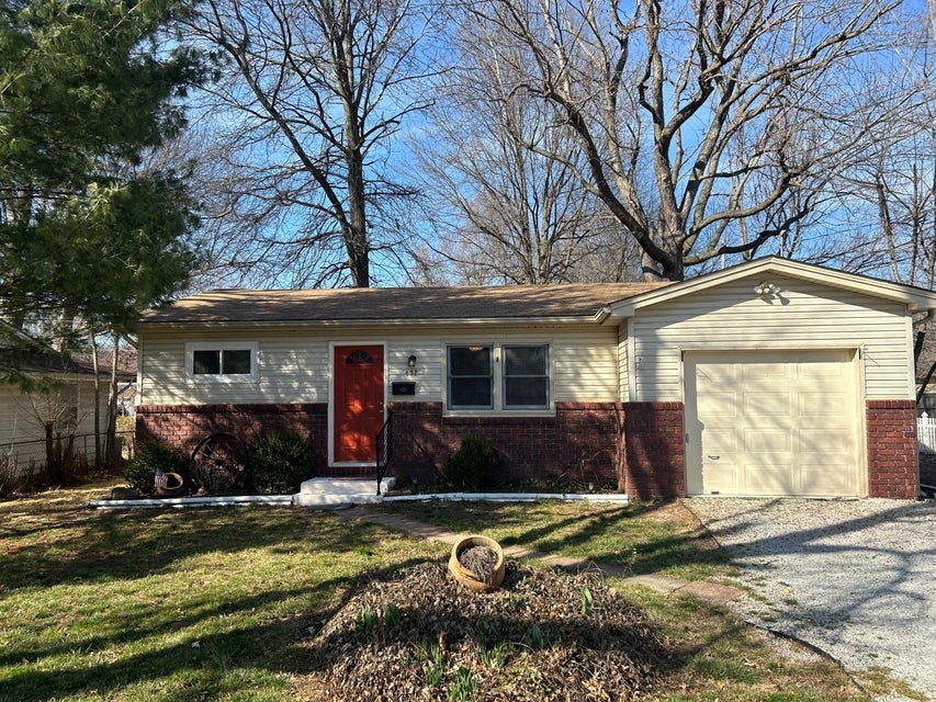 a small white house with a red door and a garage