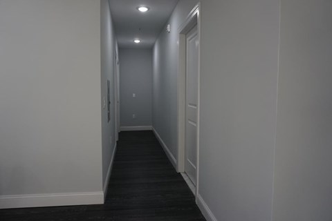 a hallway with white walls and a black carpet and white doors