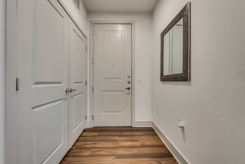 a hallway with white doors and a mirror on the wall