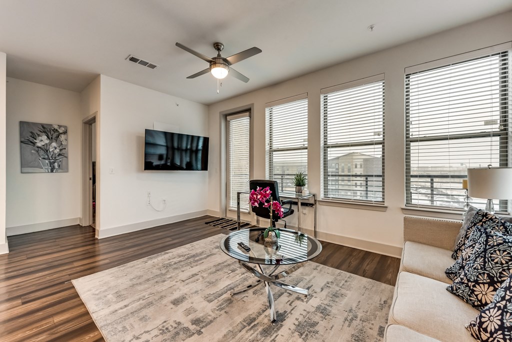 a living room with a couch and a glass coffee table and a ceiling fan