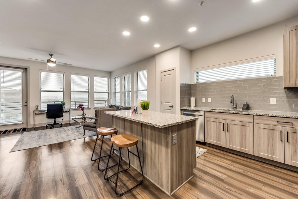 an open kitchen and living room with an island and stools