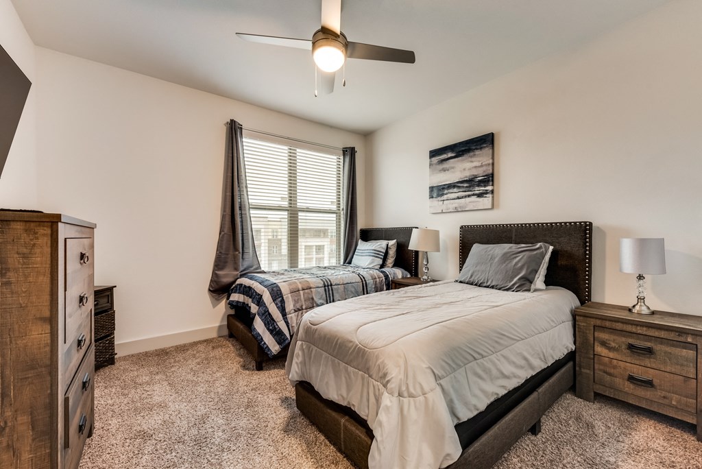two beds in a bedroom with a ceiling fan and a window
