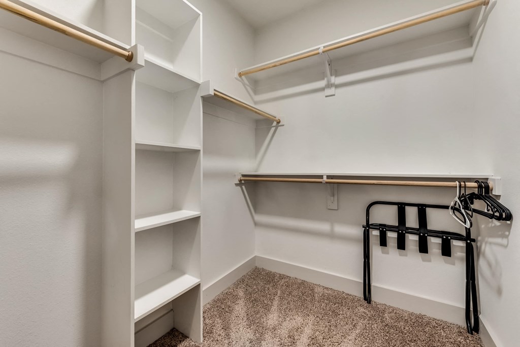 a walk in closet with shelves and a hanger rack