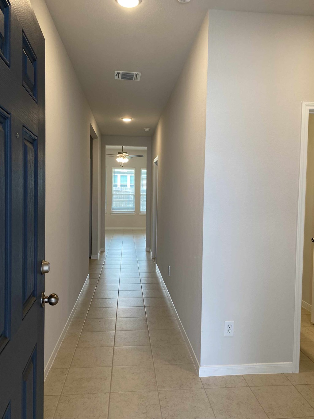 a hallway with a tiled floor and a blue door