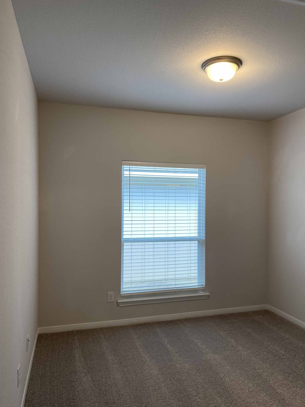 an empty living room with a large window and carpet