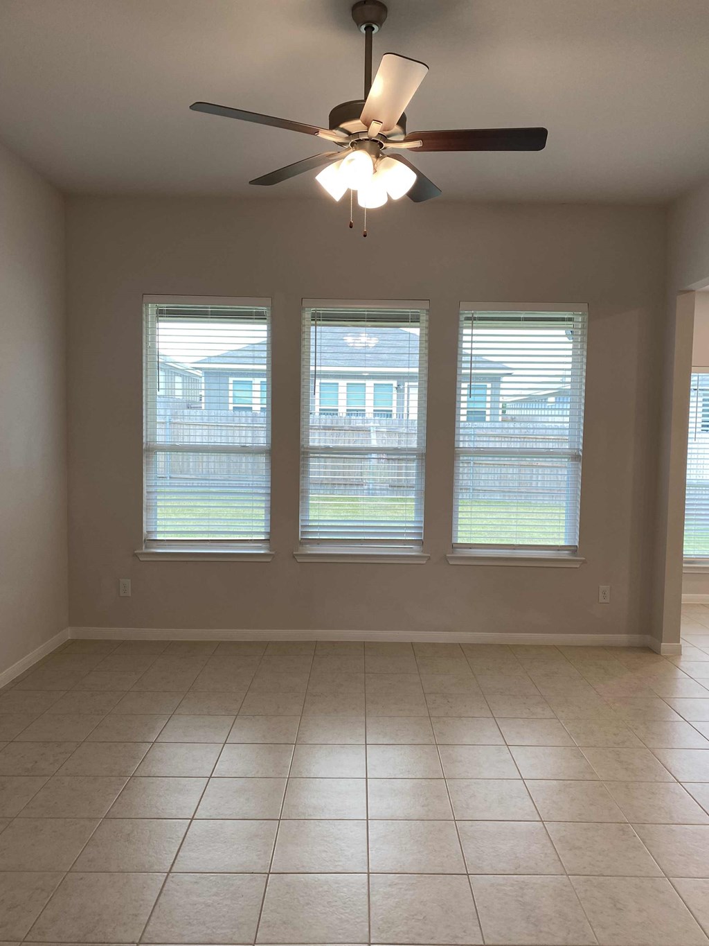 a living room with a ceiling fan and three windows