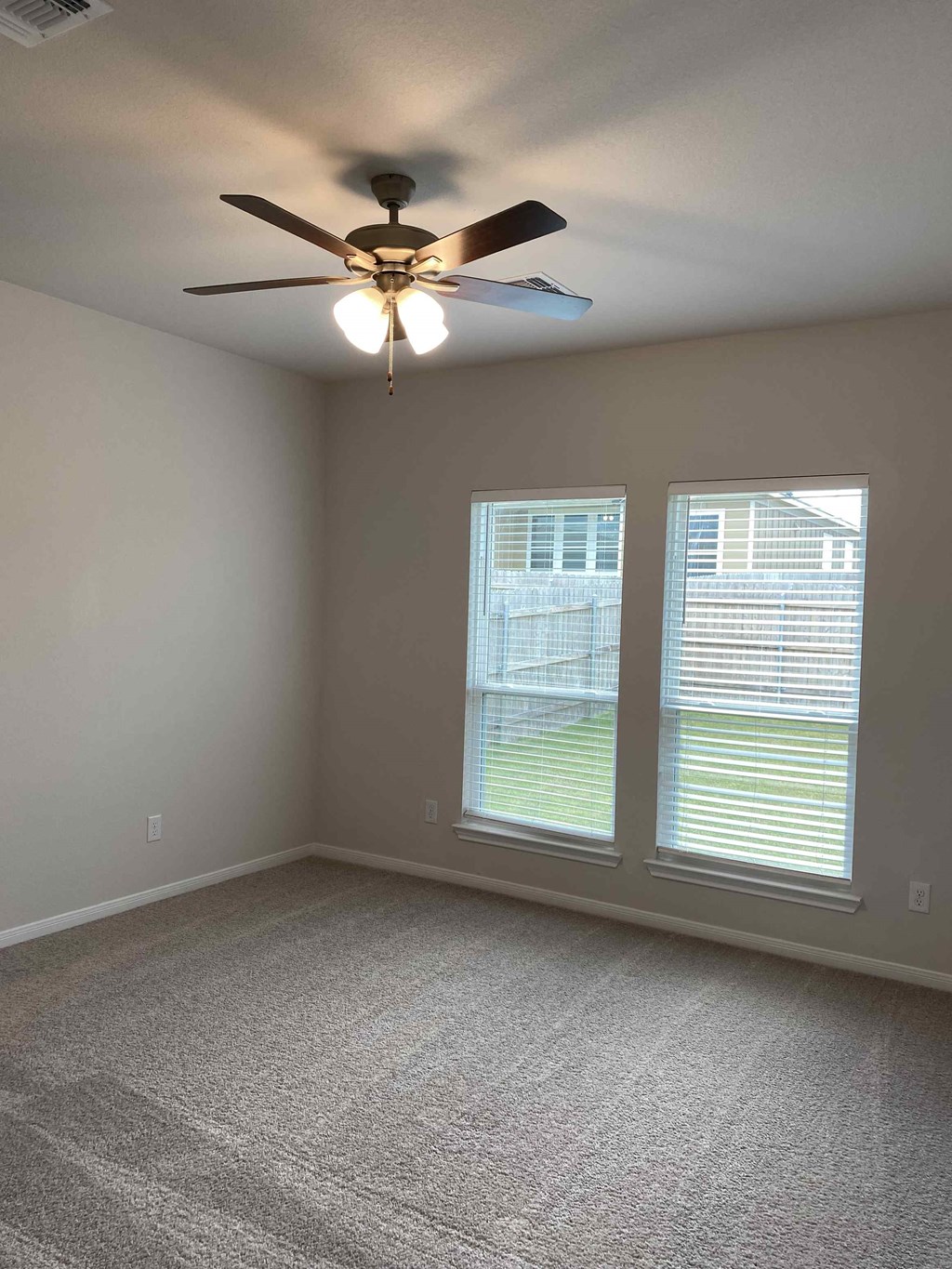 a living room with a ceiling fan and two windows
