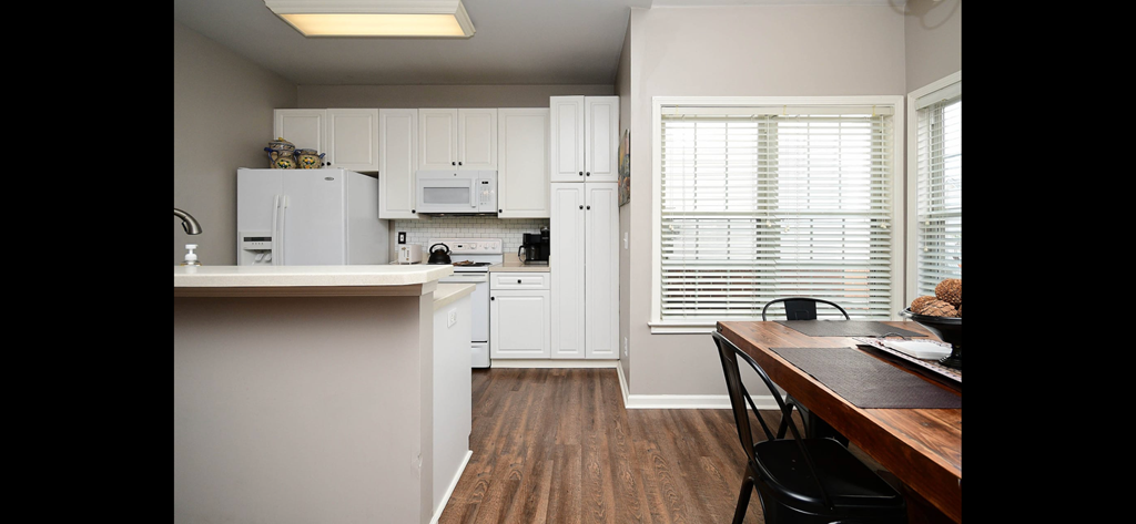 a kitchen with white cabinets and a wooden table