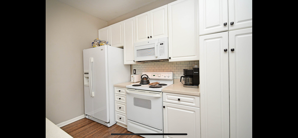 a kitchen with white cabinets and appliances and a white refrigerator