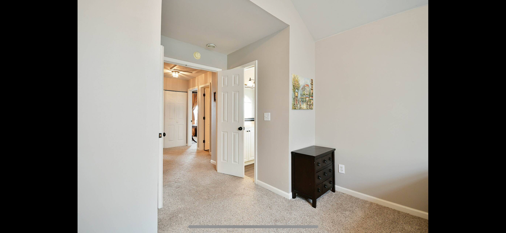 a hallway with a dresser and a hall way to a bedroom and a bathroom