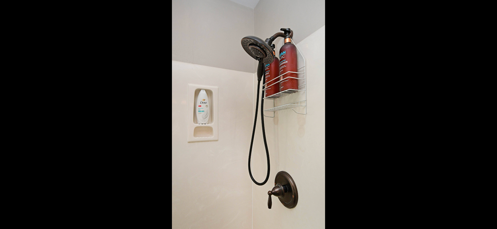a shower with a hose and a red fire hydrant on the wall