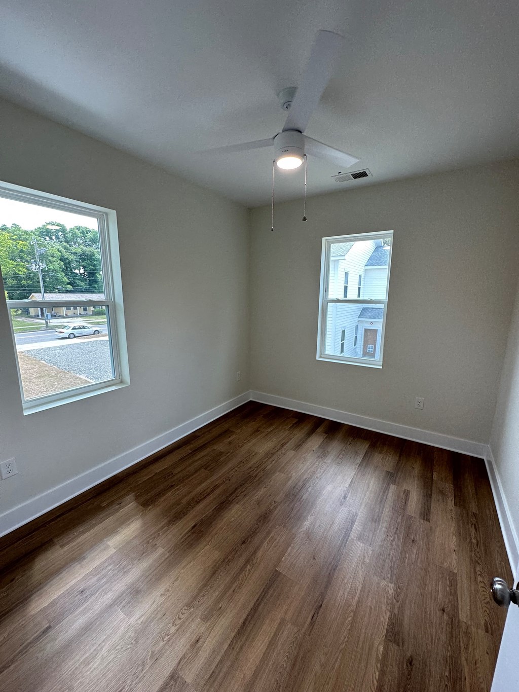 an empty living room with wood floors and a window