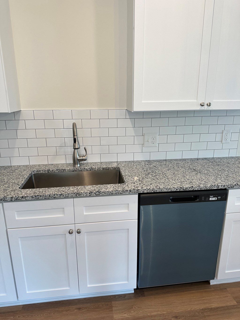 a kitchen with white cabinets and a sink and a dishwasher
