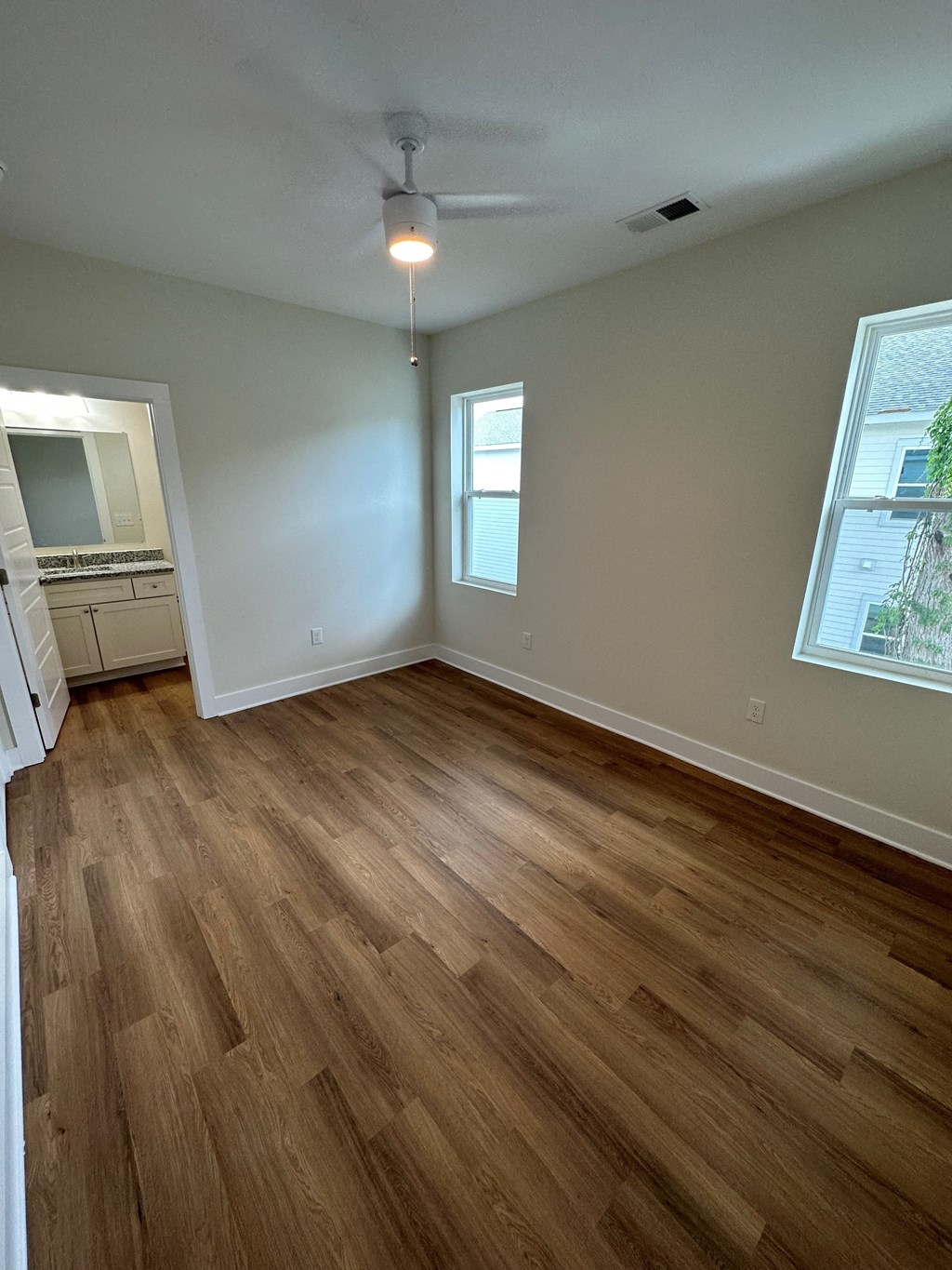 an empty living room with wooden floors and a ceiling fan