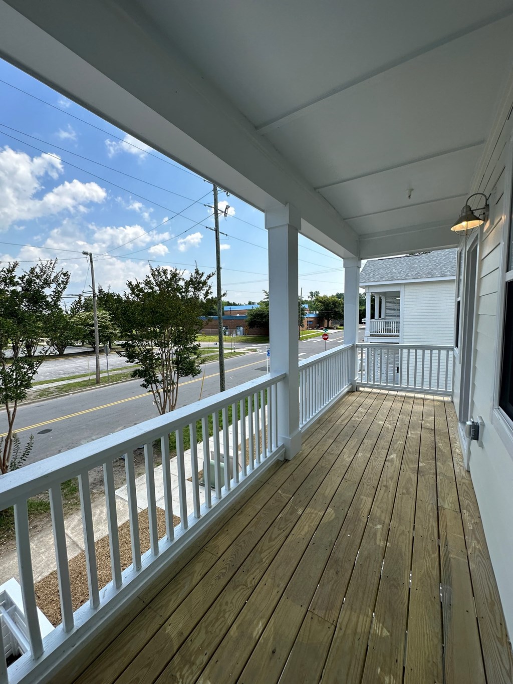 a view from the porch of a white house with a wooden deck
