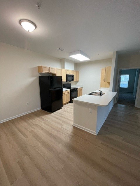 A kitchen with black appliances and wooden floors.