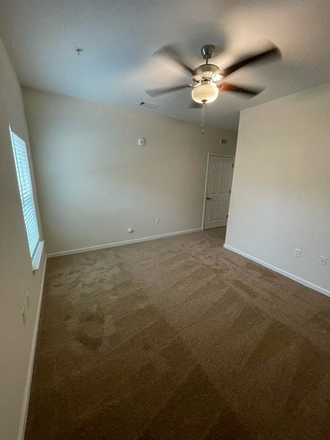 A room with a ceiling fan and carpeted floor.