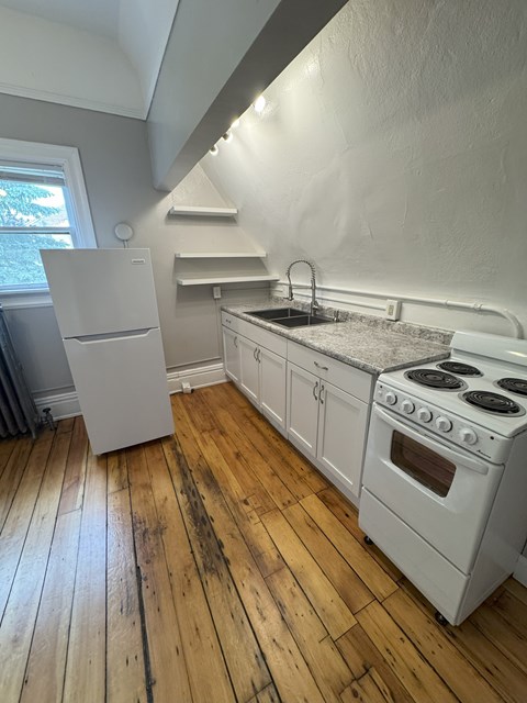 A kitchen with a white stove and refrigerator.