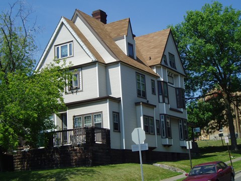 A white house with a red car parked in front.